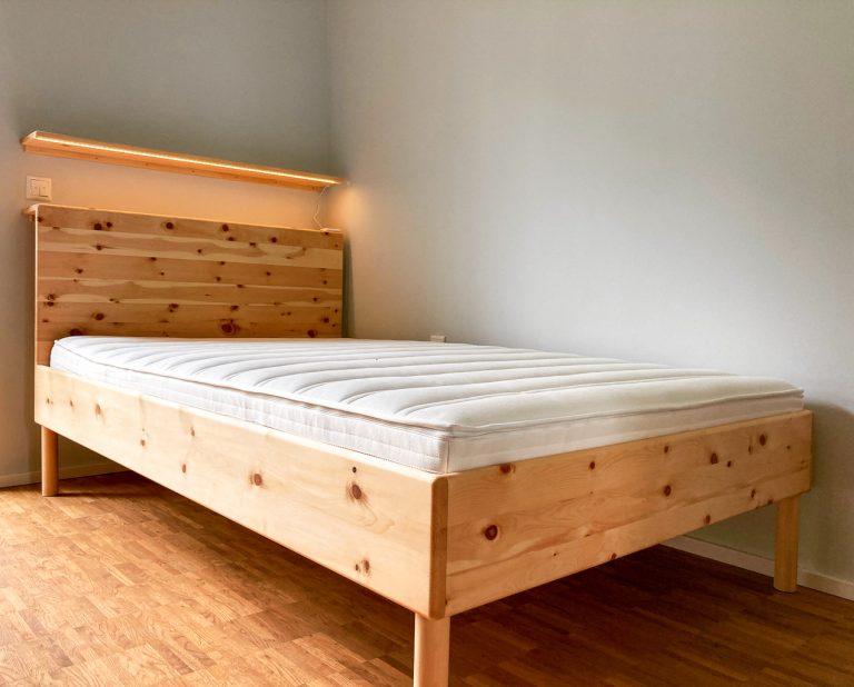Bettgestell aus hellem Holz mit breitem Kopfteil